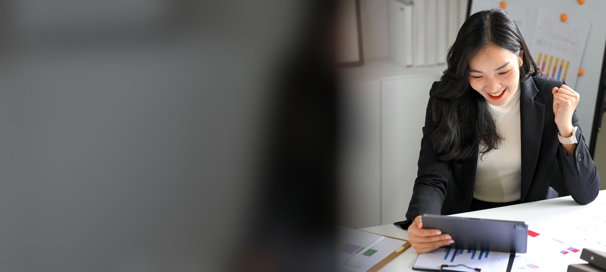 Sales professional celebrating a win at her desk with a tablet